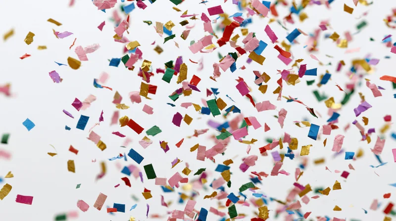 Colorful paper confetti pieces falling and floating mid-air against a white background