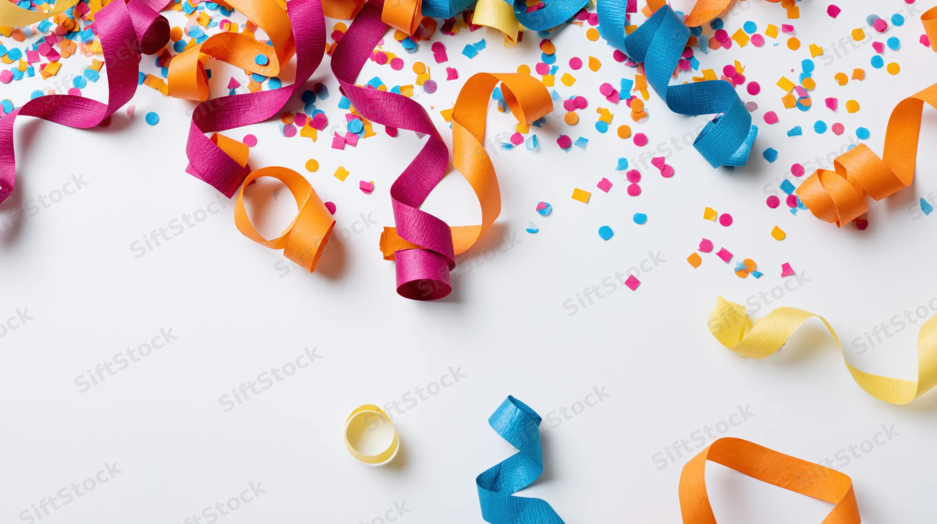 Colorful paper streamers and confetti scattered on white surface with copyspace