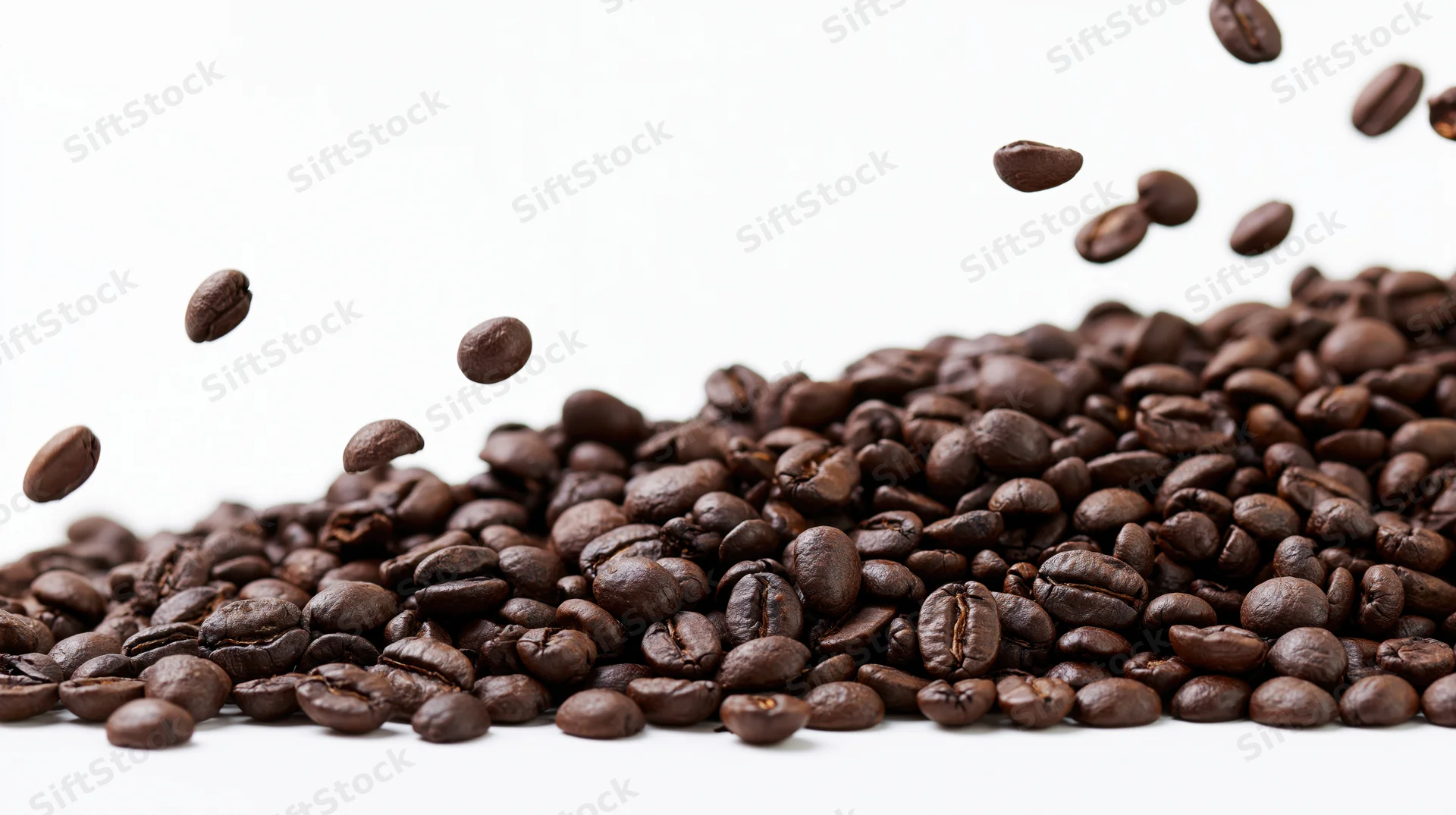 Dark roasted coffee beans falling and scattered in a pile on white background