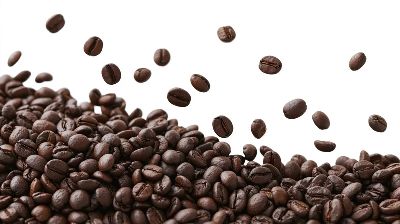 Dark roasted coffee beans falling and scattered in a pile against a white background
