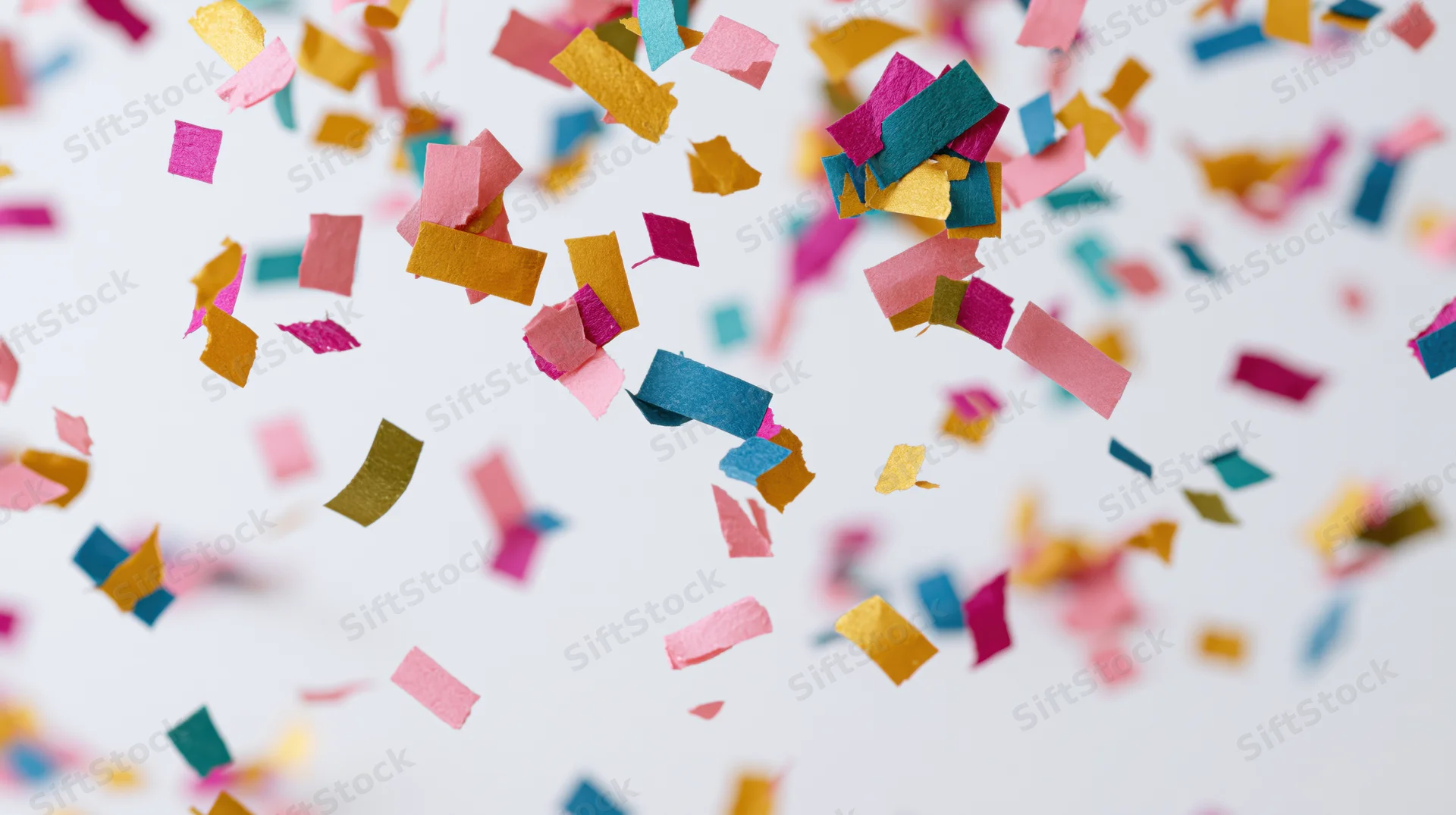 Colorful paper confetti pieces falling midair against a white background