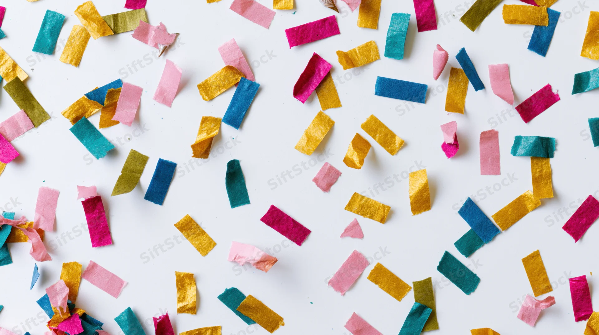 Colorful paper confetti scattered across a white surface in a flat lay overhead view