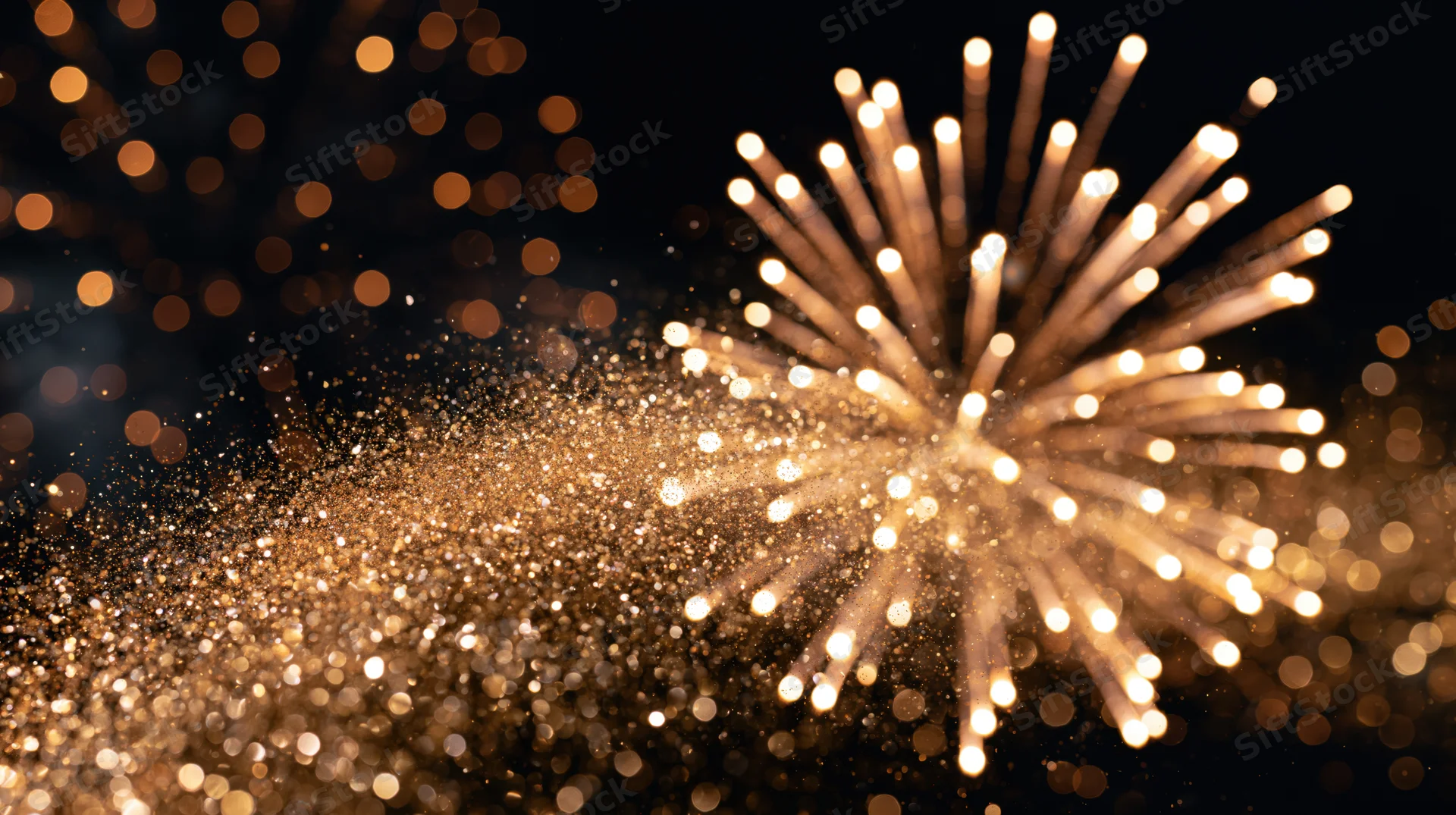 Fireworks bursting in dark night sky with golden sparkles and bokeh lights