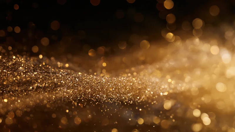 Golden glitter particles shimmering in soft focus against dark background