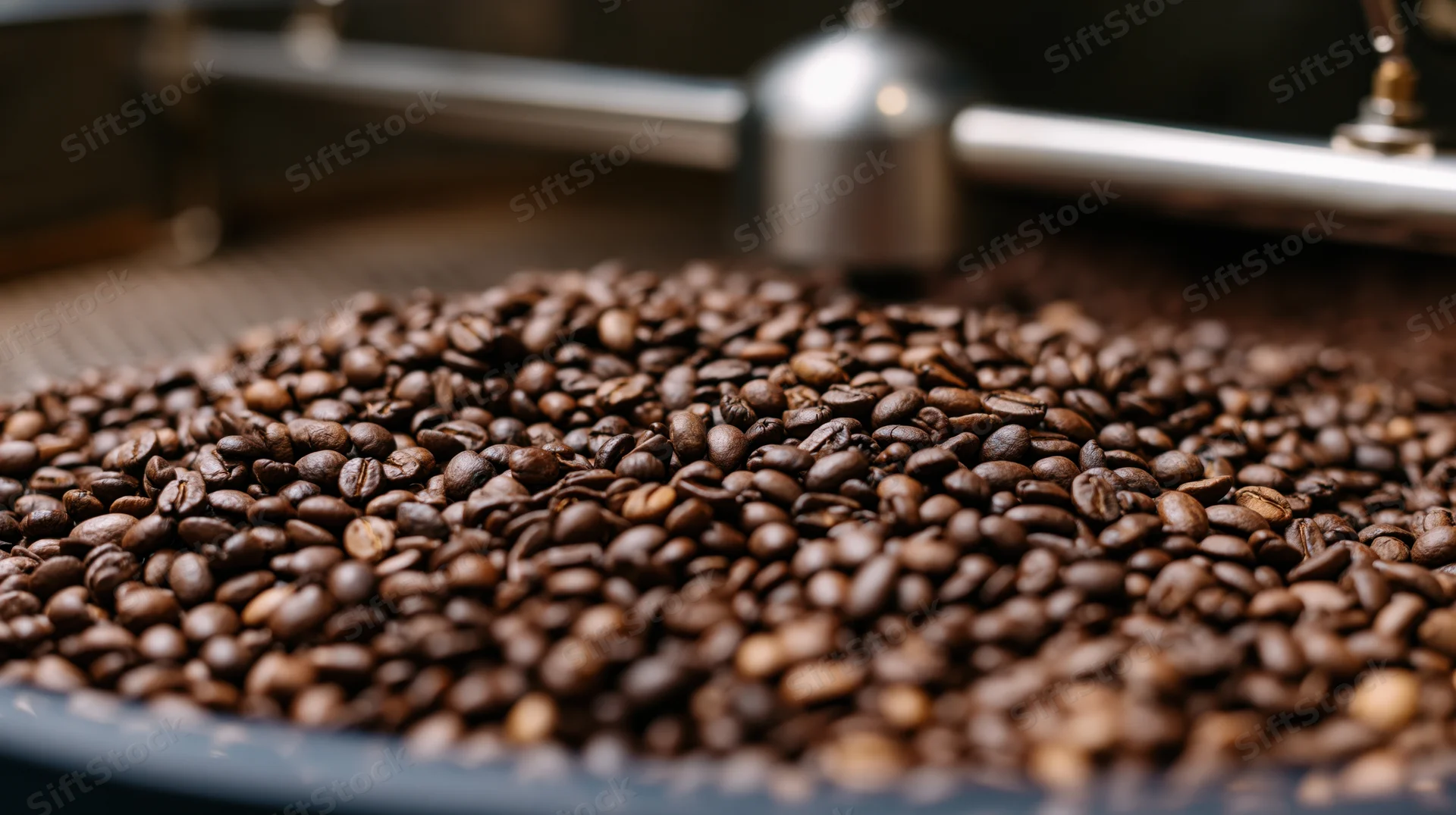 Roasted coffee beans piled in a cooling tray inside an industrial roasting facility