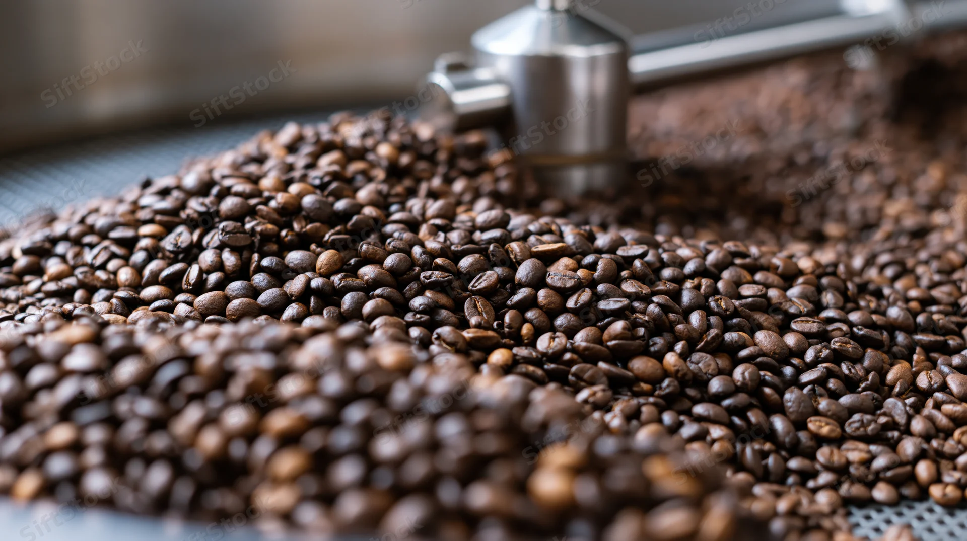 Roasted coffee beans piled on a metal cooling tray in an industrial roasting facility