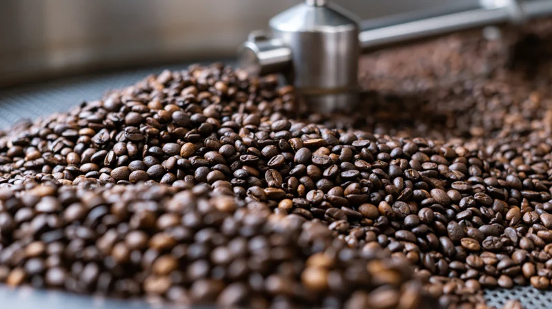Roasted coffee beans piled on a metal cooling tray in an industrial roasting facility