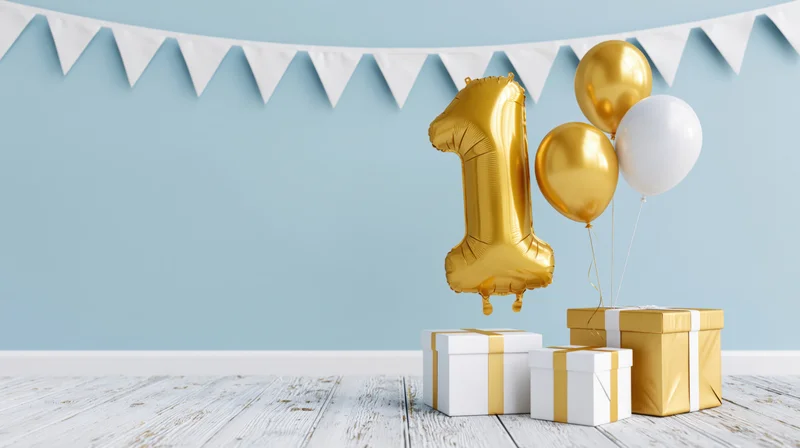 Gold number-one balloon floating beside gift boxes and white pennant banner on blue wall and wooden floor