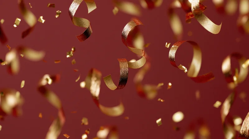 Gold metallic ribbon confetti and foil pieces falling against a red background