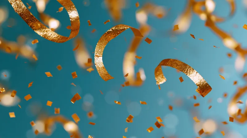 Gold metallic streamers and confetti falling against a blue background