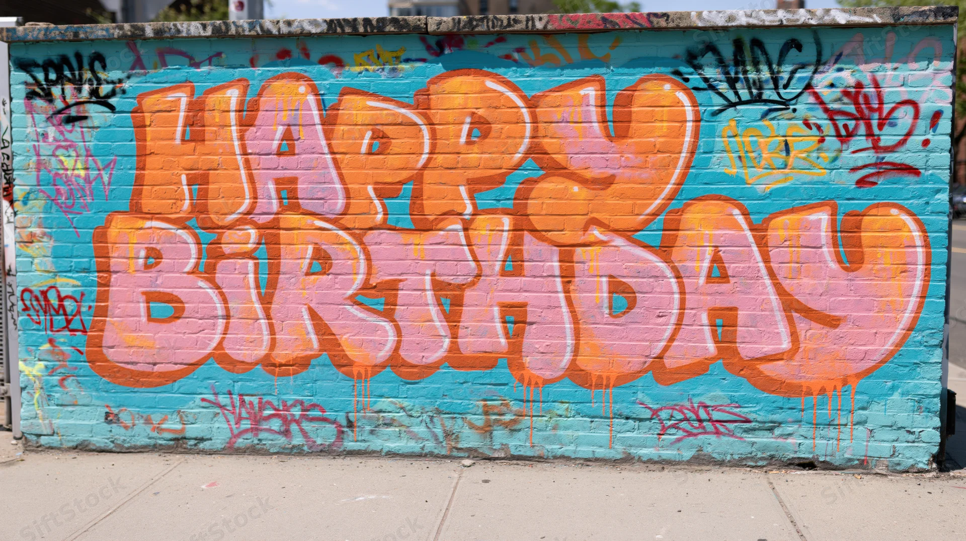 Happy birthday graffiti lettering spray-painted on a brick wall in an urban outdoor setting