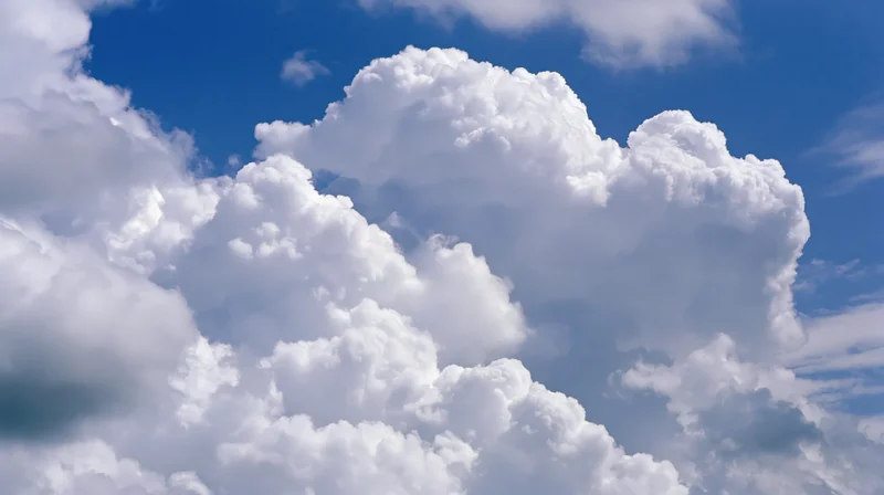 Large cumulus clouds billowing upward against a clear blue sky
