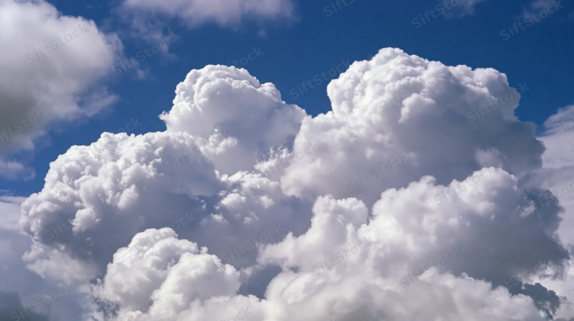 Large cumulus clouds billowing upward against a clear blue sky