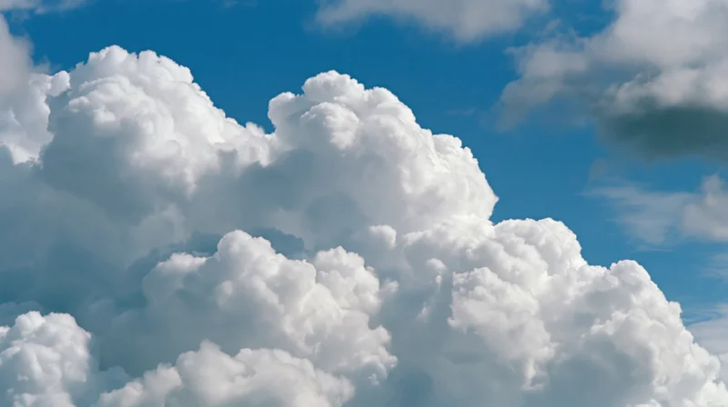 Large cumulus clouds billowing upward against a clear blue sky