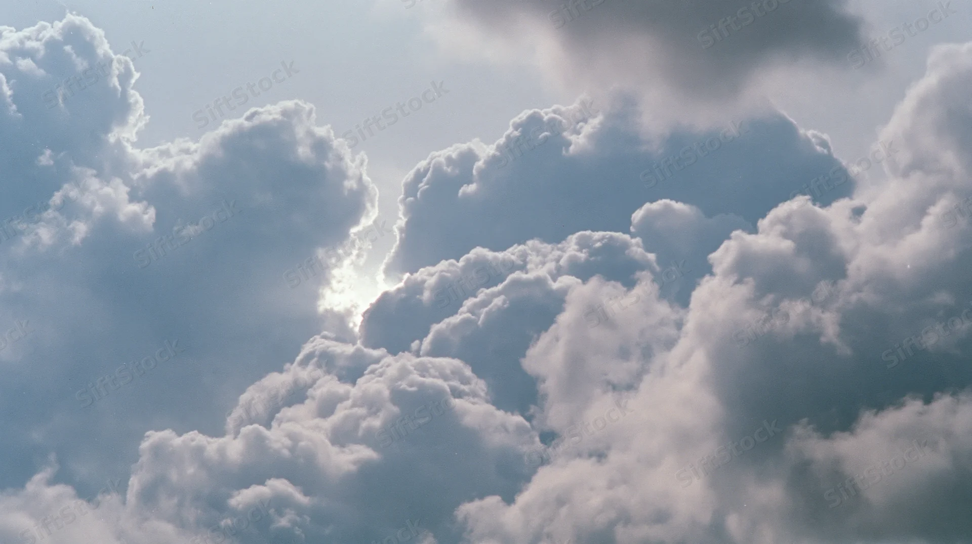 Large cumulus clouds billowing across the sky with sunlight breaking through