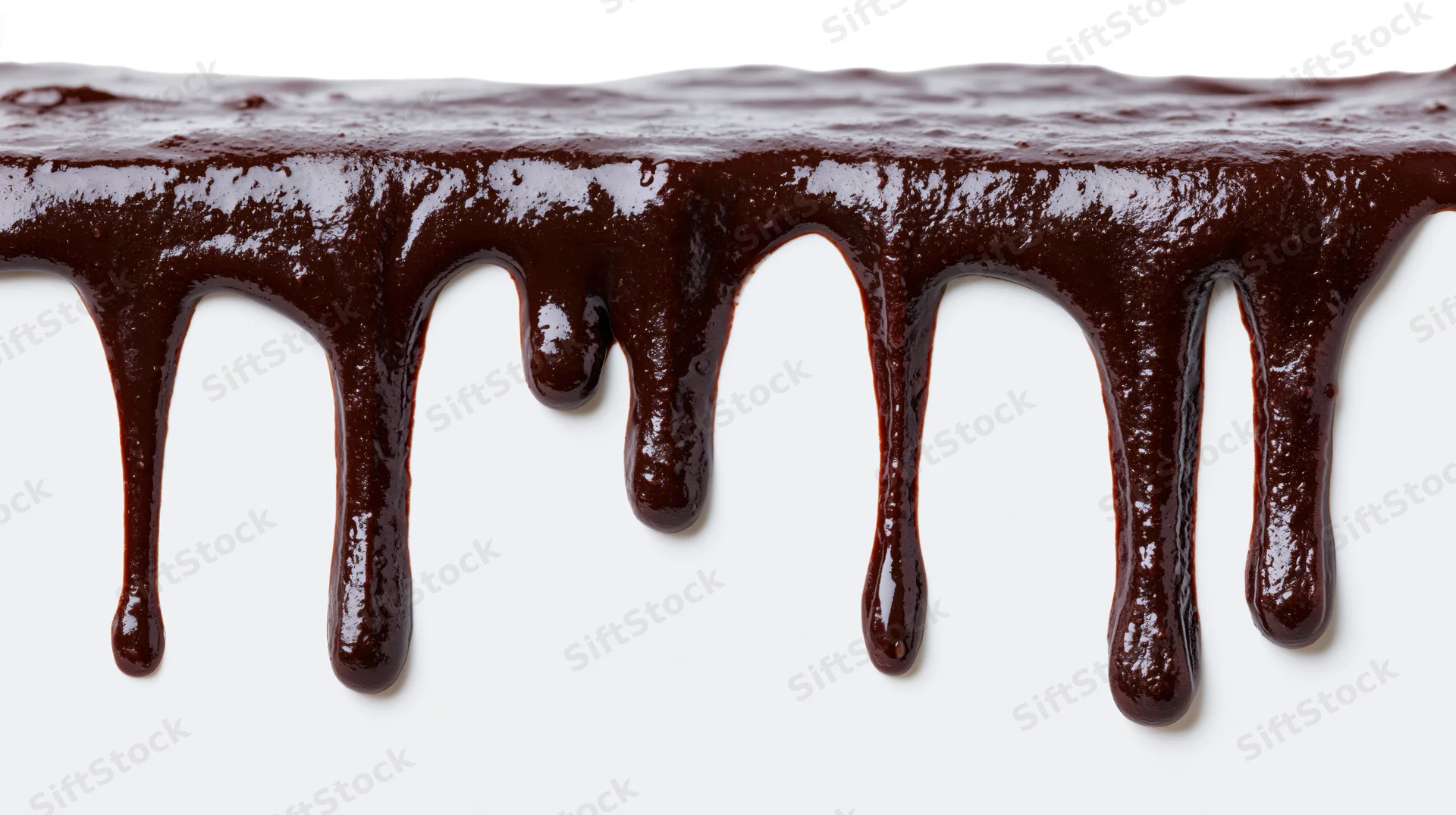Melted dark chocolate dripping in multiple streams against a white background