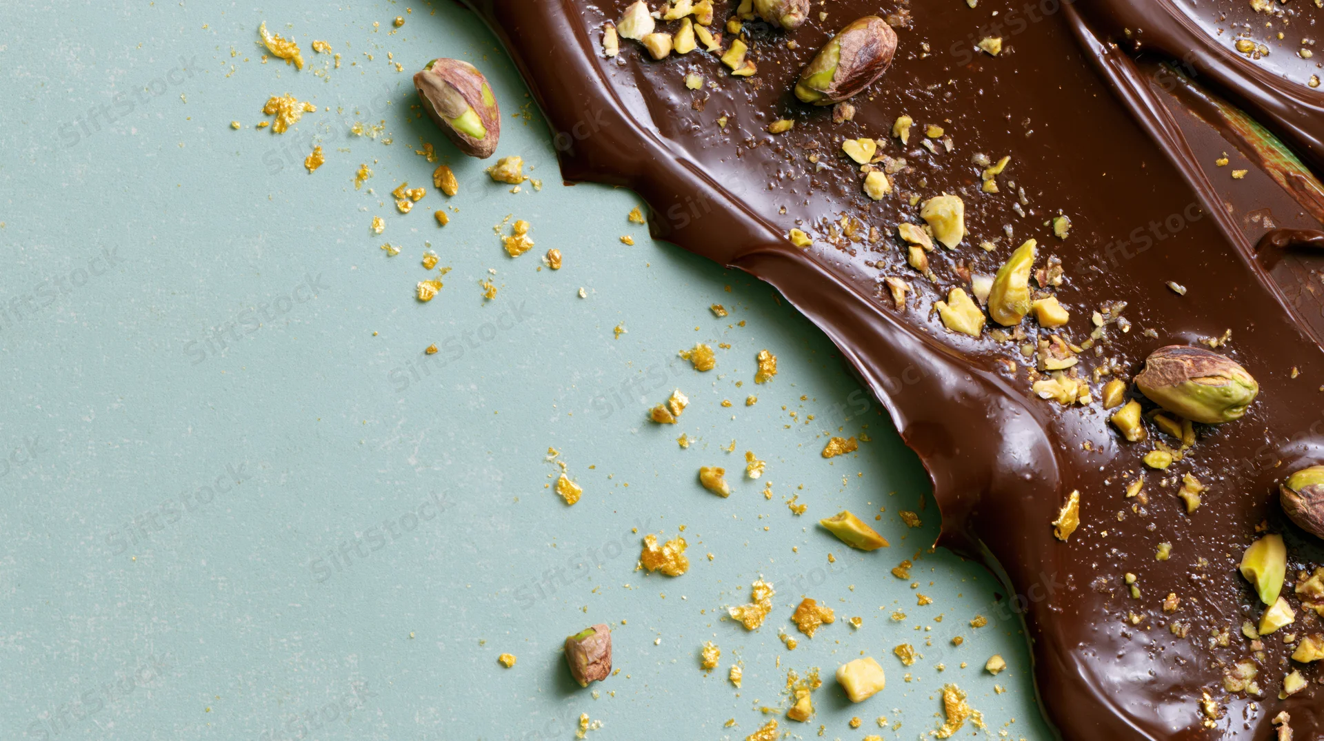 Melted dark chocolate spread with pistachios on a sage green surface