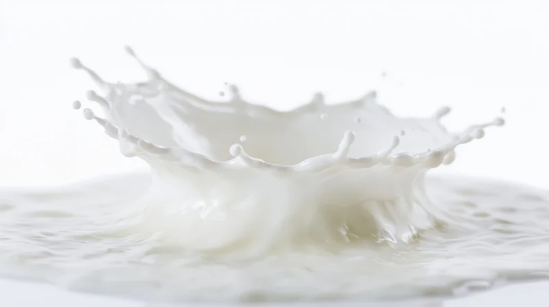 Milk splash forming a crown shape mid-air above a flat pool of milk