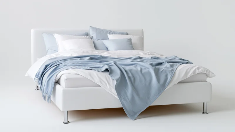 Modern double bed with white upholstered frame and chrome legs in a minimalist studio setting