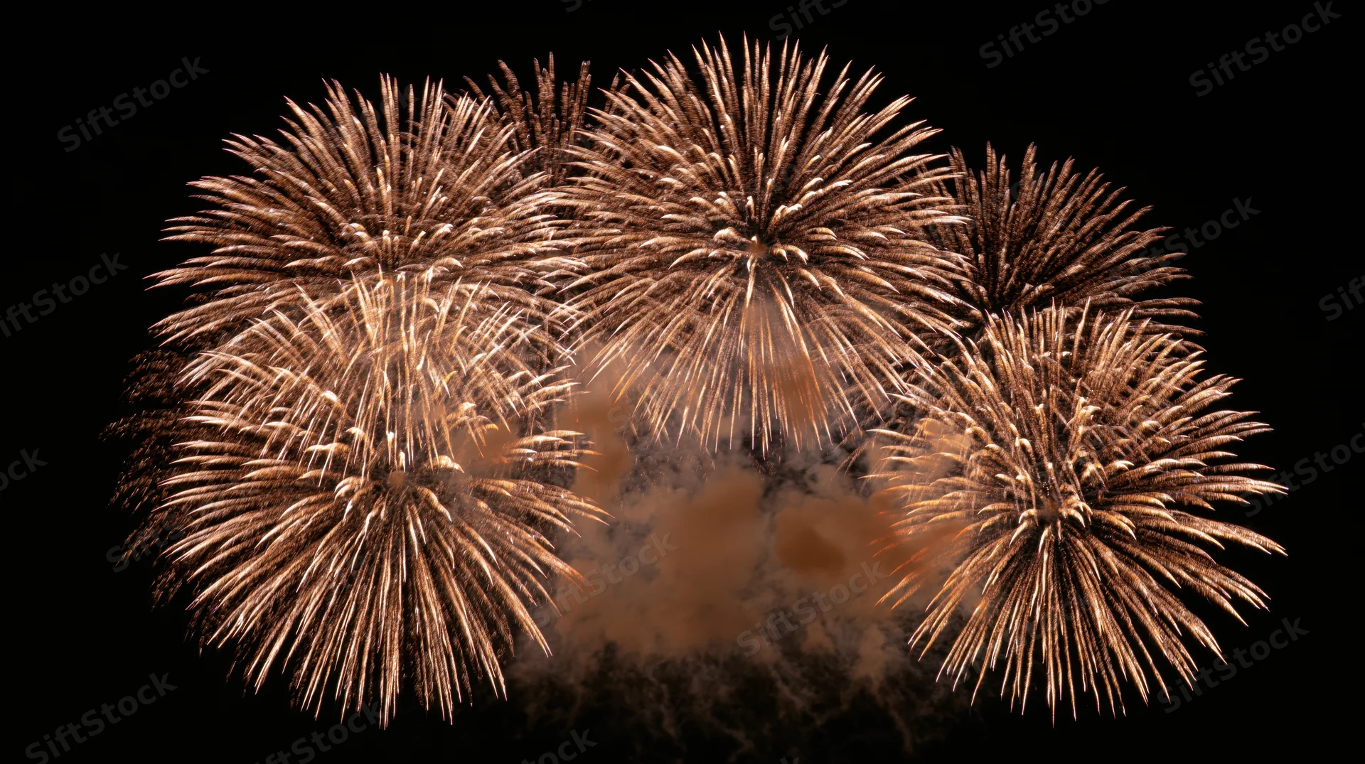Multiple fireworks bursting simultaneously against a dark sky