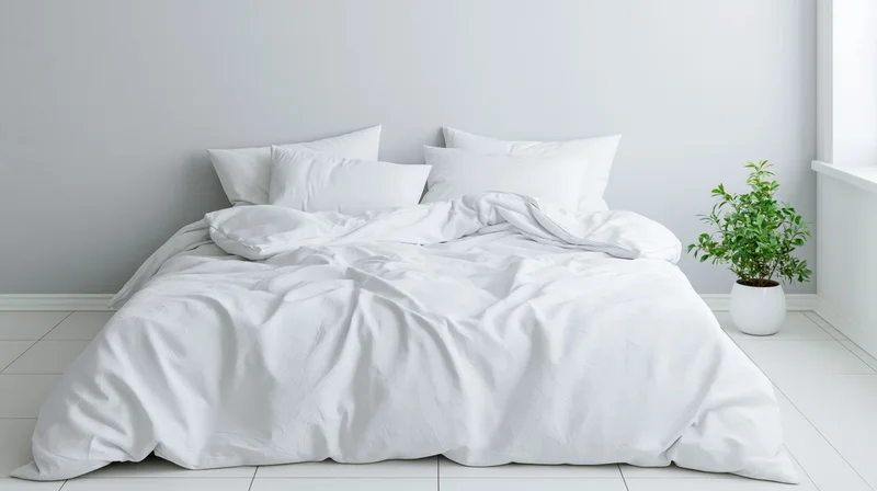 Unmade bed with white cotton duvet and four pillows in minimalist bedroom