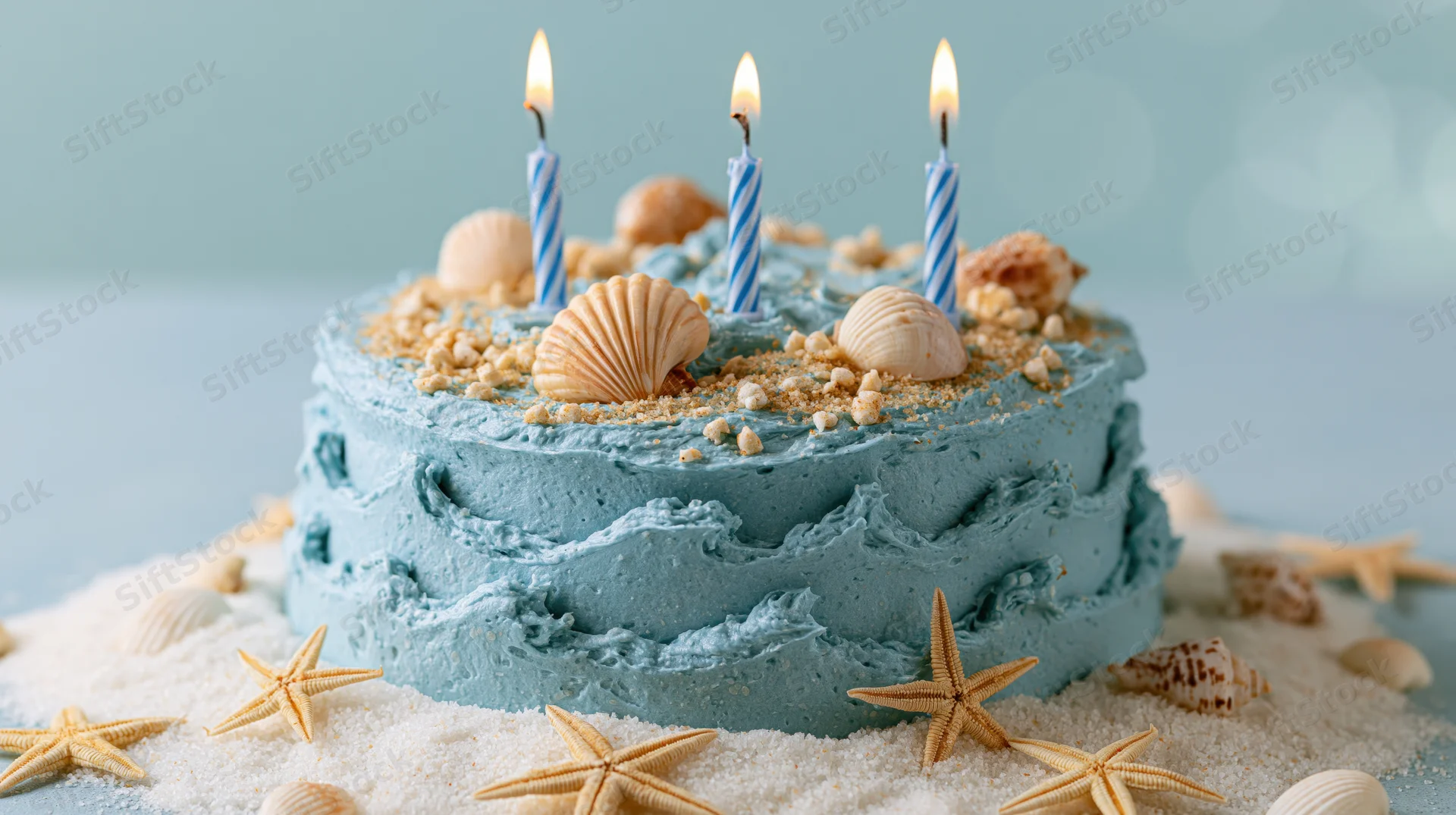 Ocean-themed birthday cake with blue frosting and seashells on sand base