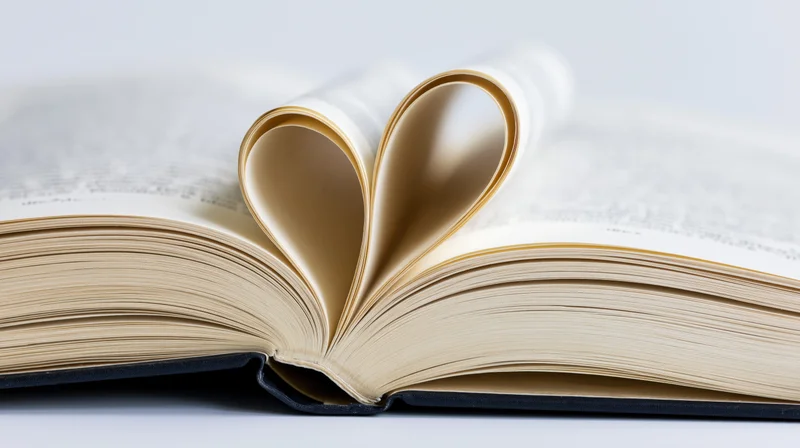 Open hardcover book with center pages folded into a heart shape on a white surface
