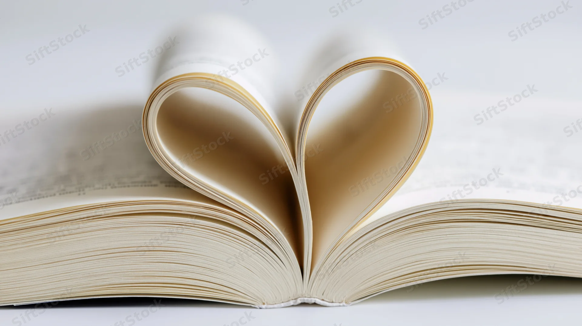 Open hardcover book with center pages folded into a heart shape on a white surface