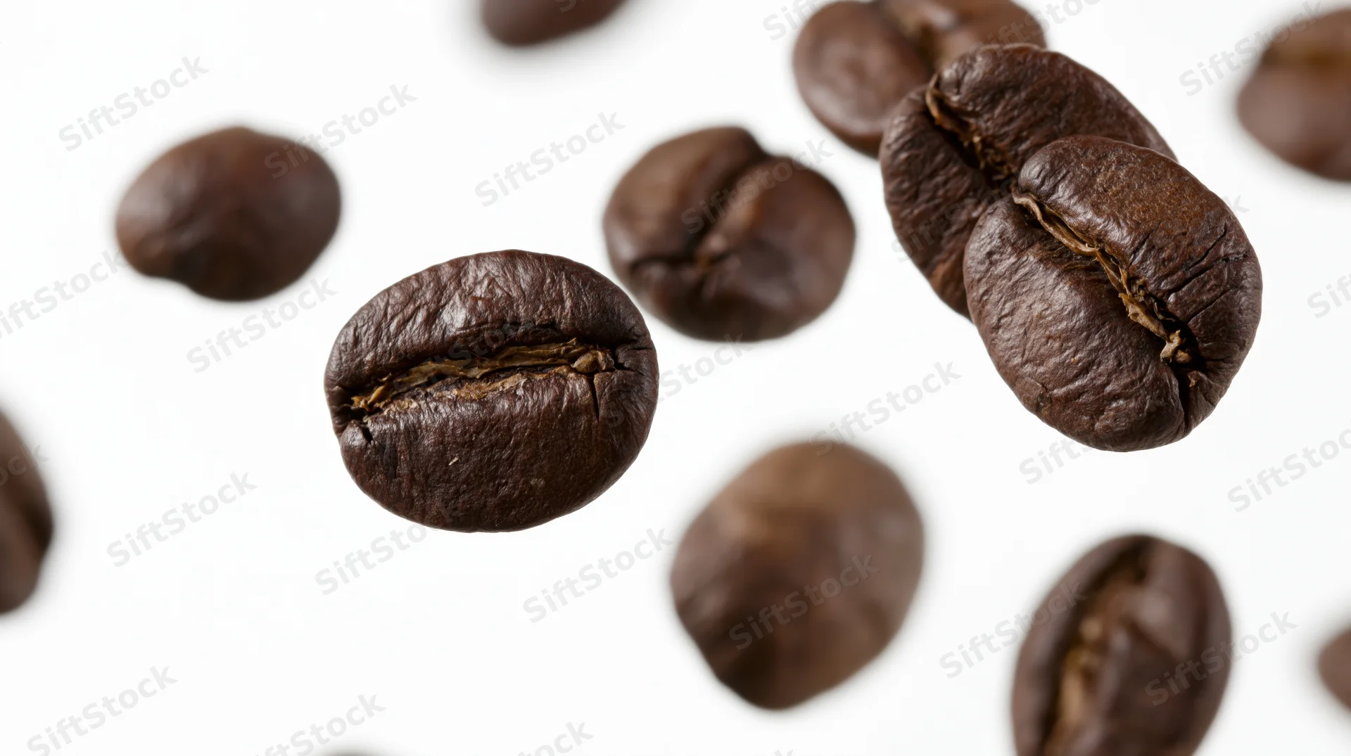 Roasted coffee beans floating midair scattered against white background