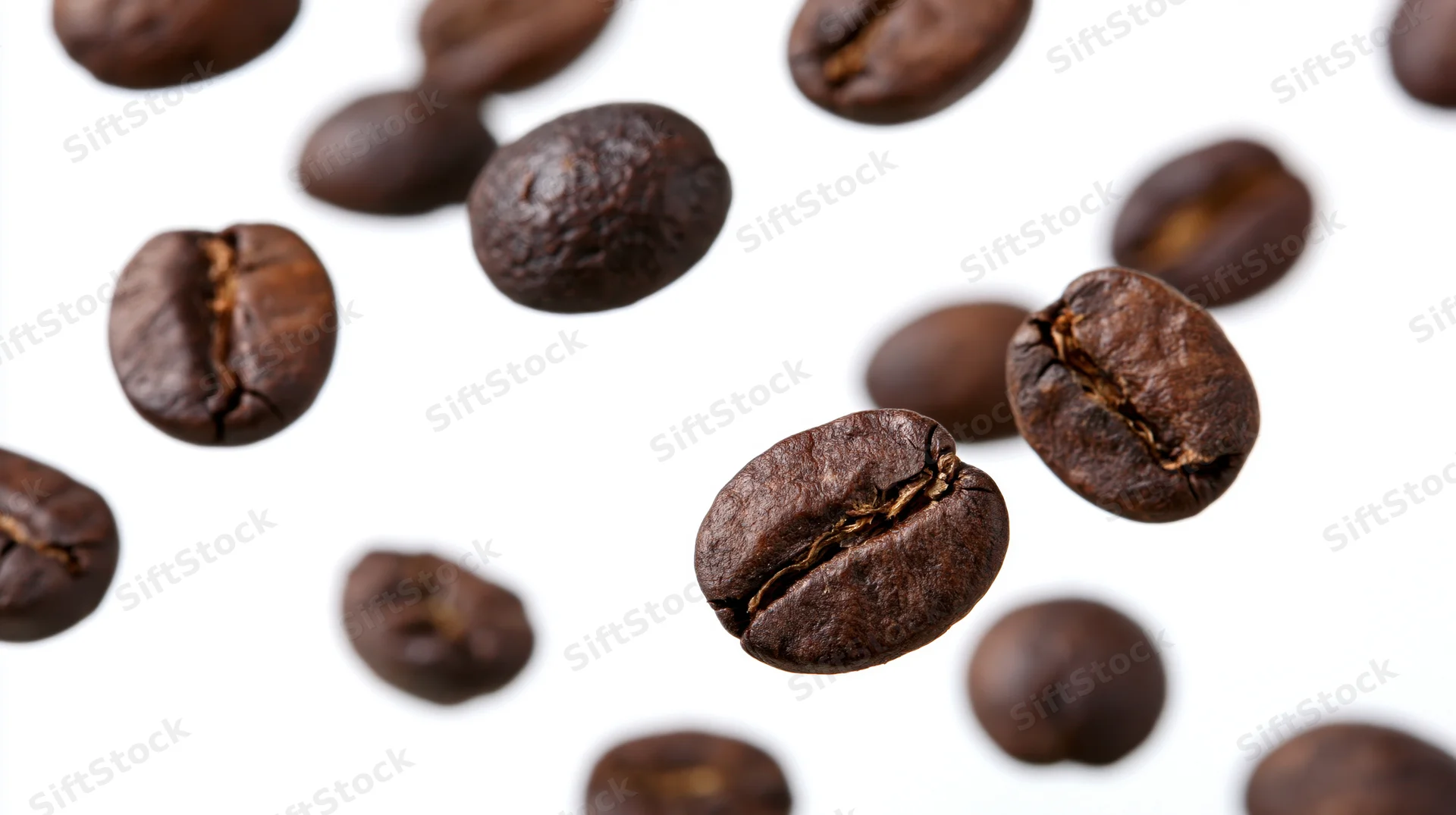 Roasted coffee beans floating midair scattered against white background