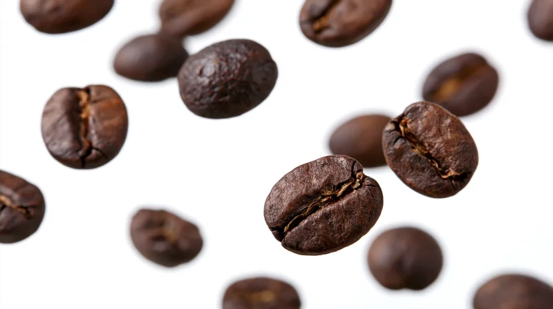 Roasted coffee beans floating midair scattered against white background