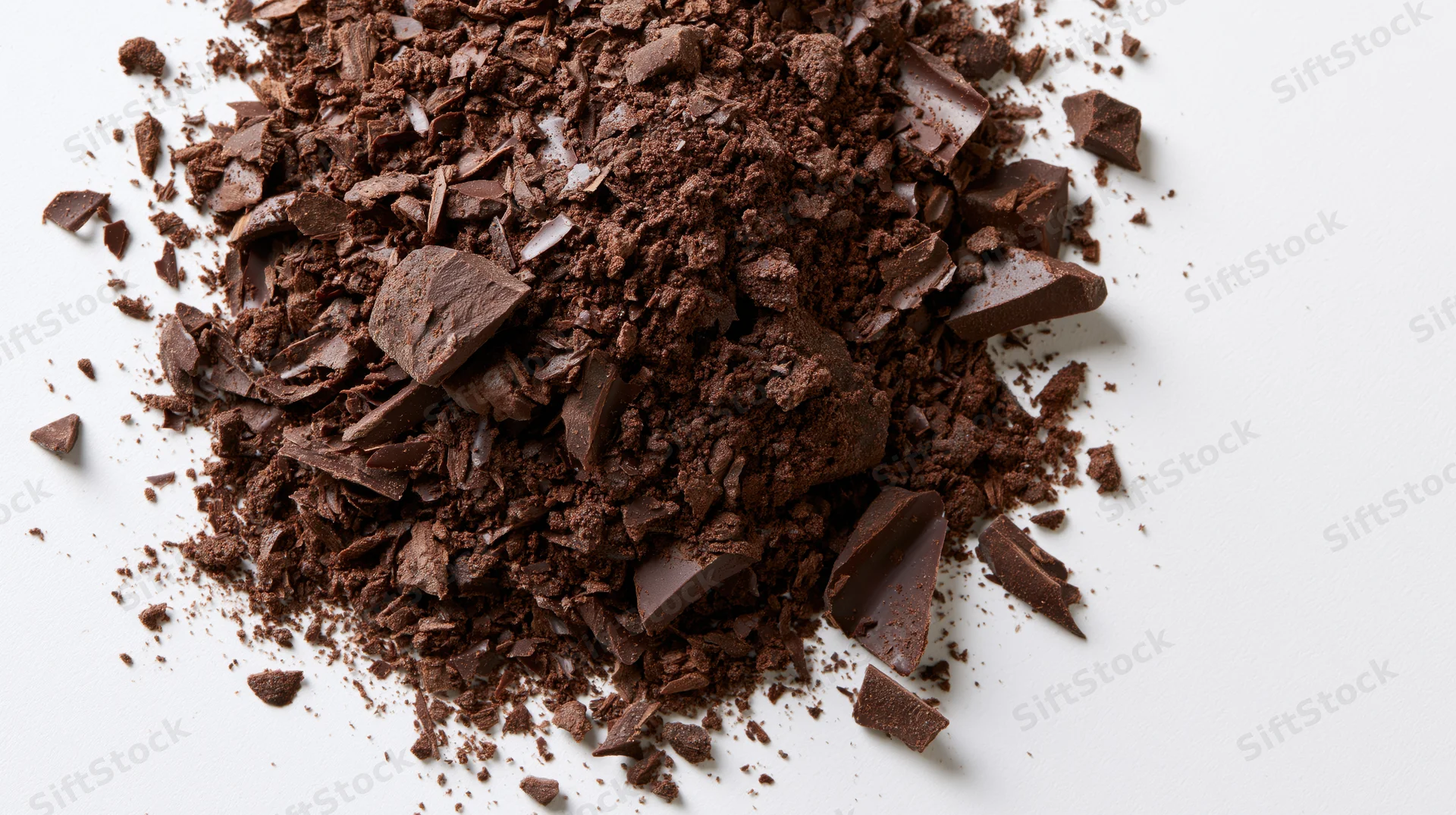 Scattered pile of dark chocolate shavings and coarse chunks on white background