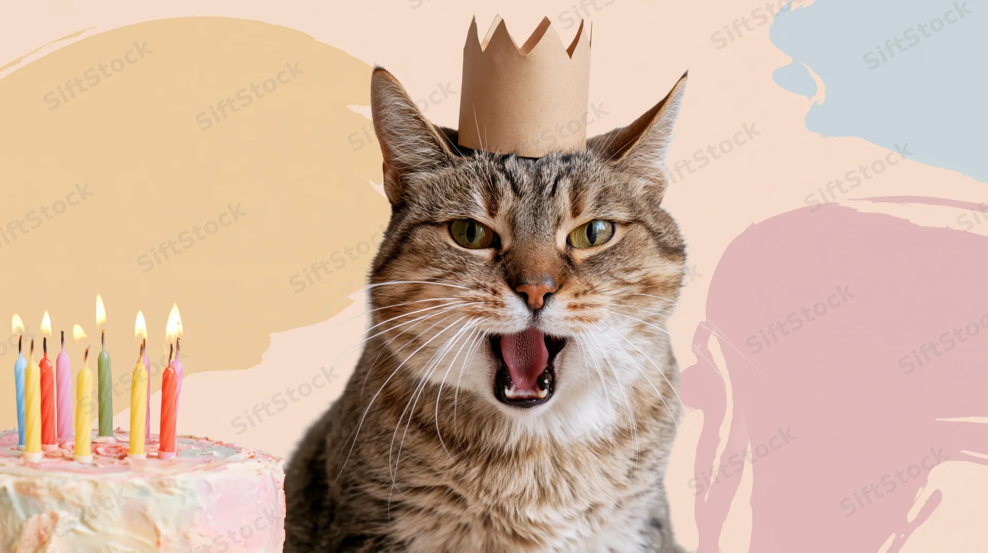 Tabby cat wearing paper crown with open mouth beside birthday cake with lit candles on pastel background