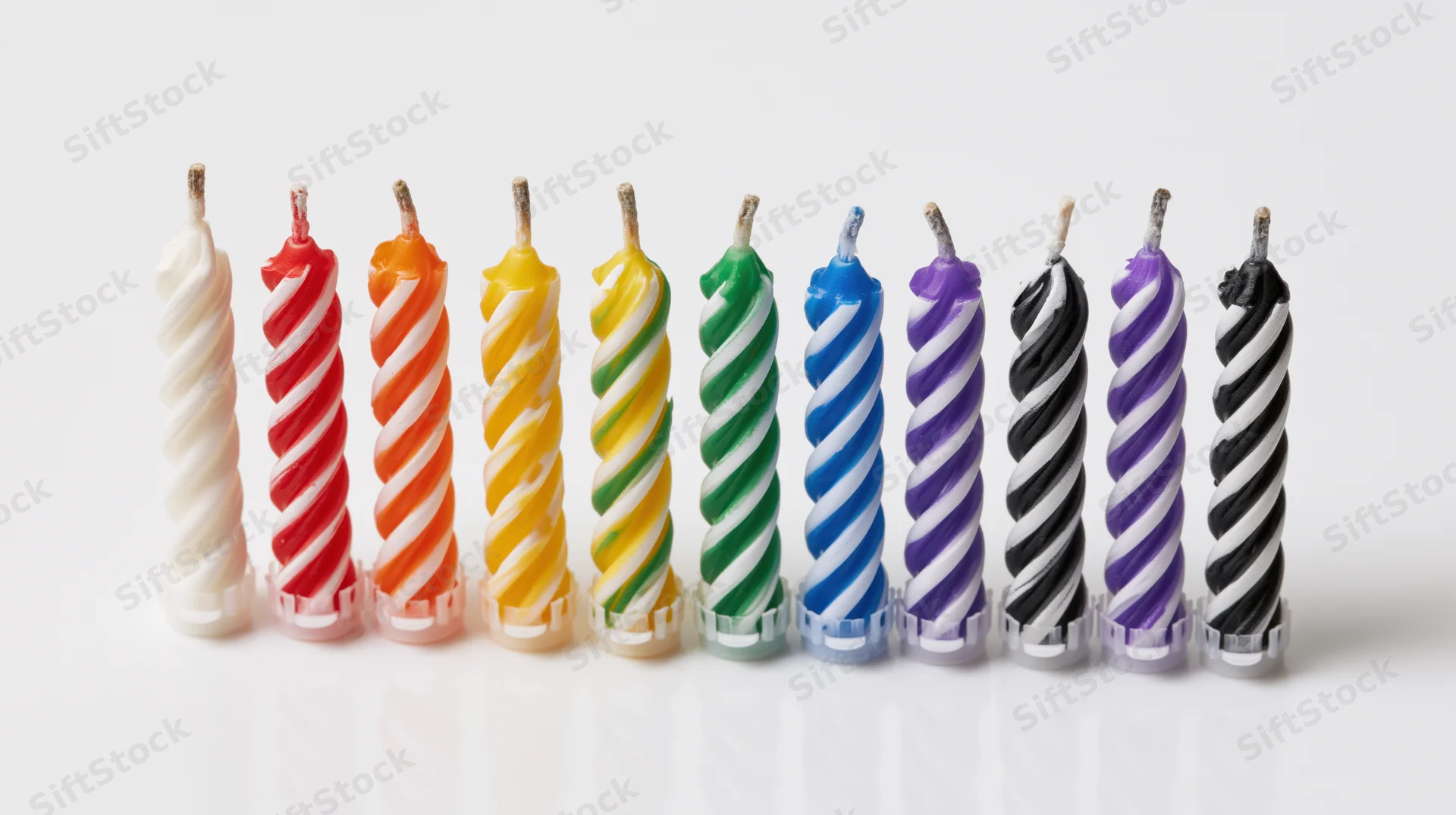 Ten unlit spiral striped birthday candles arranged in a row on white background
