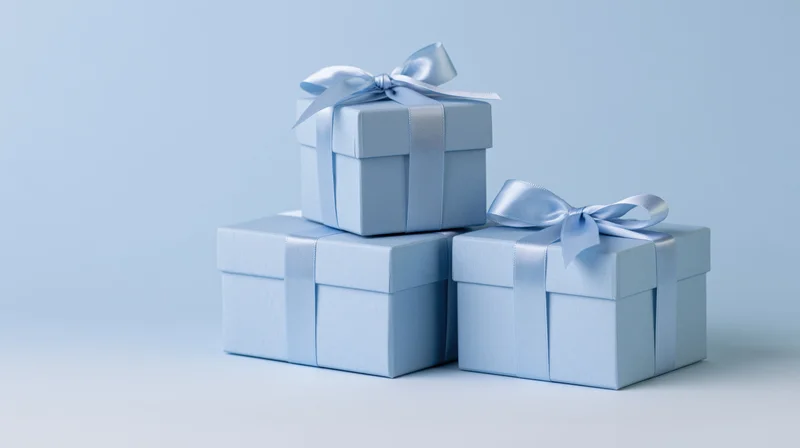 Three light blue gift boxes stacked with ribbons and bows on a plain background