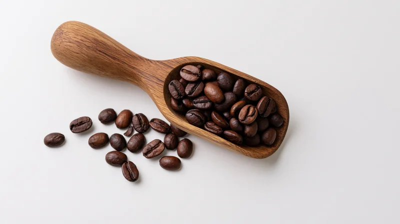Wooden scoop filled with roasted coffee beans on white surface