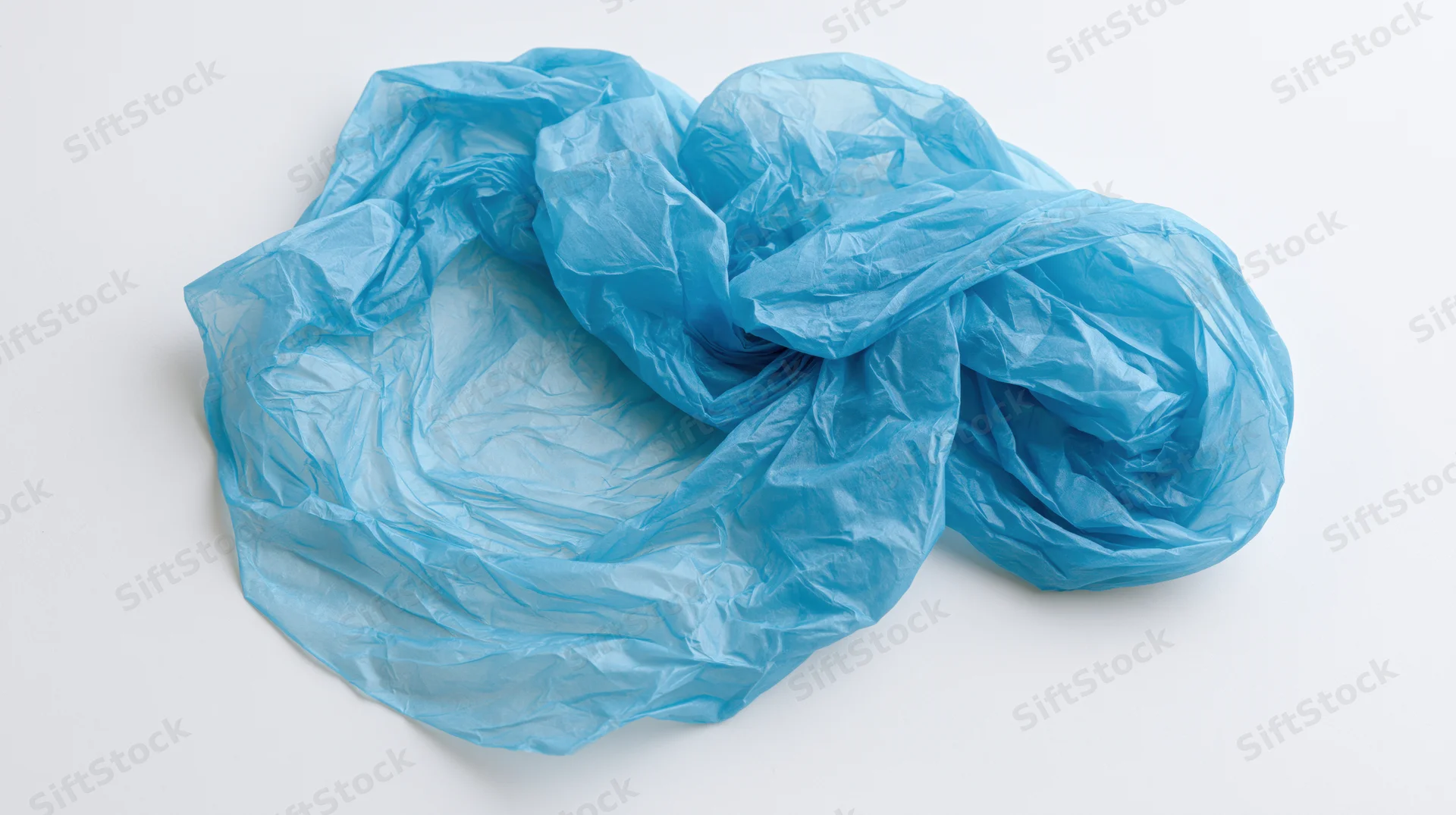 Crumpled blue plastic bag lying flat on white surface
