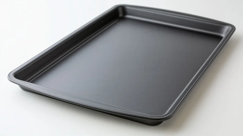 Dark grey nonstick baking sheet pan resting empty on white surface
