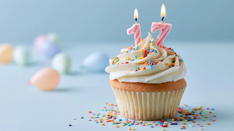 Birthday cupcake with number seventeen candles and sprinkles on a pastel background