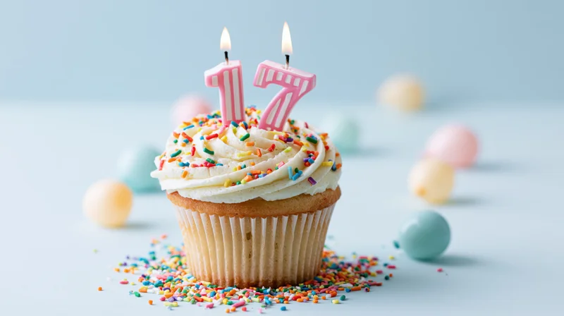 Birthday cupcake with number 17 candles and sprinkles on light blue surface