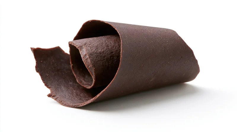 Dark chocolate curl shaving resting on white background