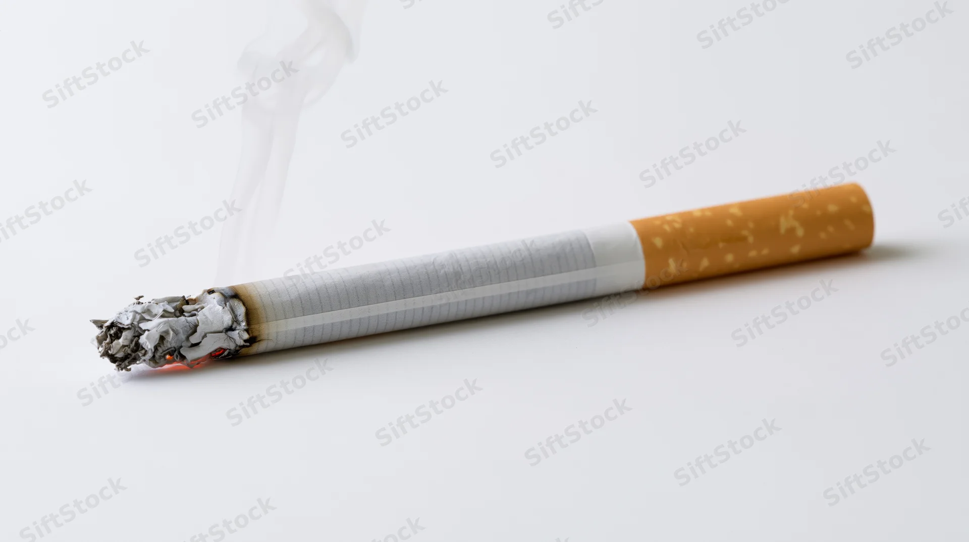 Lit cigarette burning horizontally with smoke rising on white background