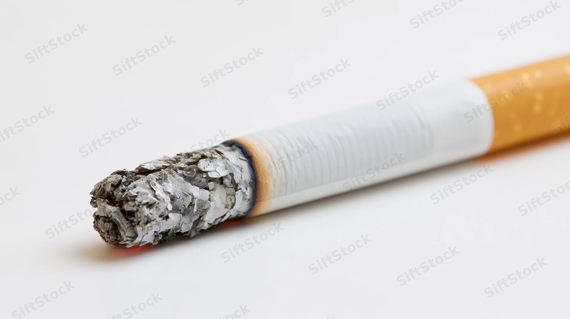 Lit cigarette with glowing ash tip on white background