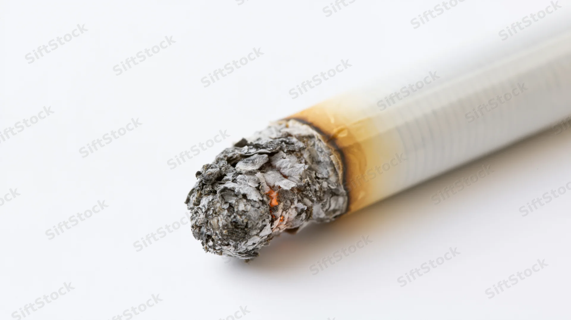 Lit cigarette with glowing ash tip on white background