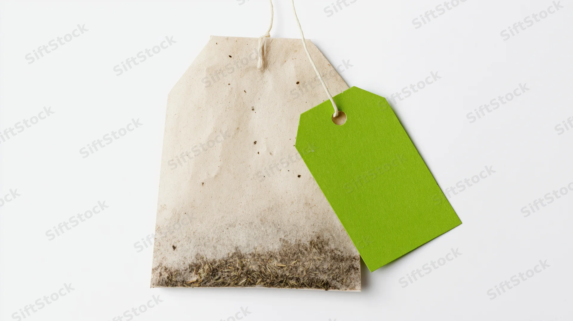 A single unused tea bag with a bright green paper tag attached, isolated on white background
