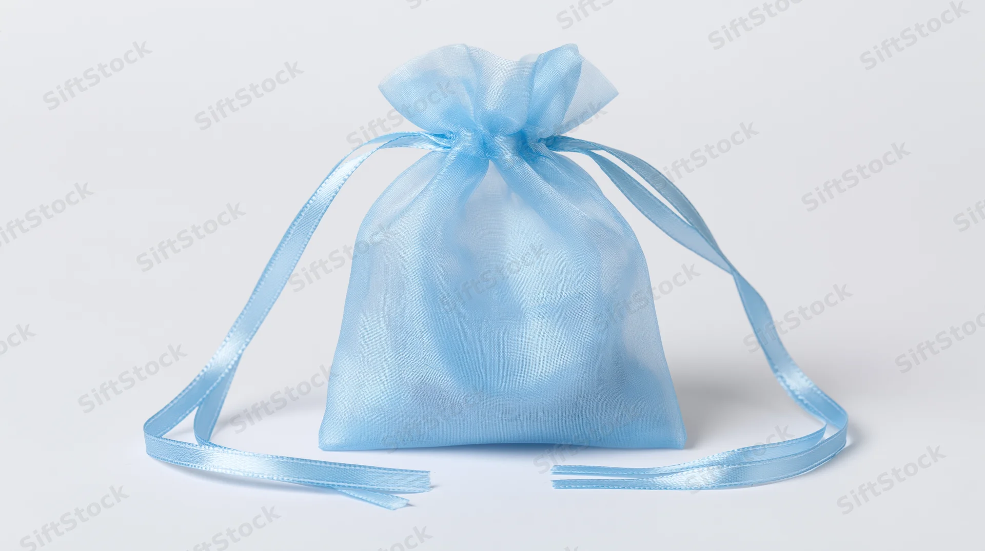 Light blue organza drawstring gift bag standing upright on white surface