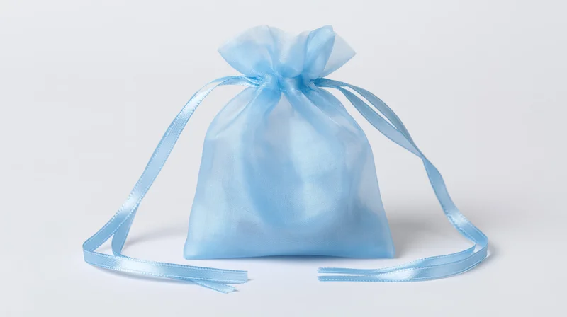 Light blue organza drawstring gift bag standing upright on white surface