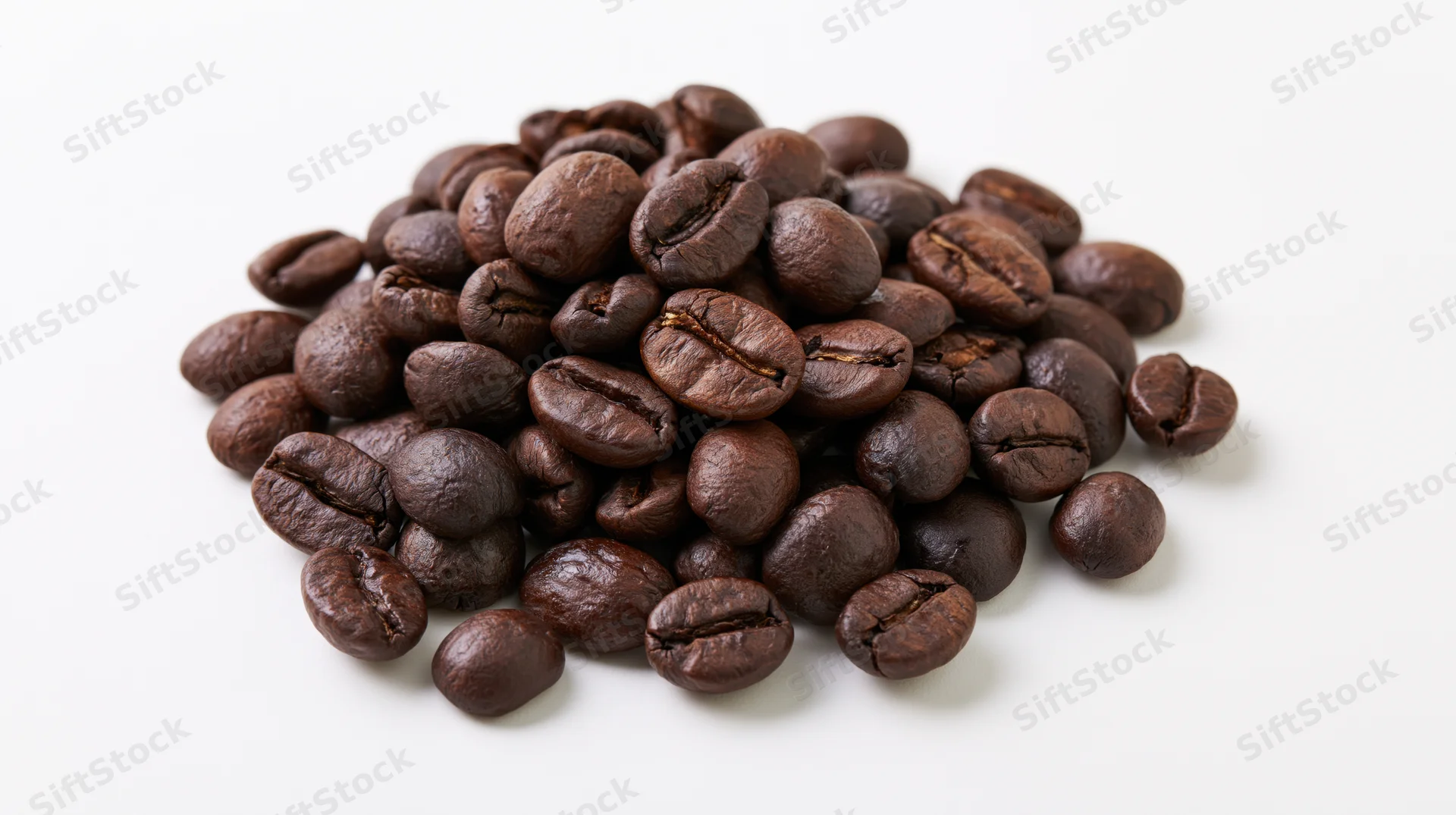 Dark roasted coffee beans piled loosely on a white surface