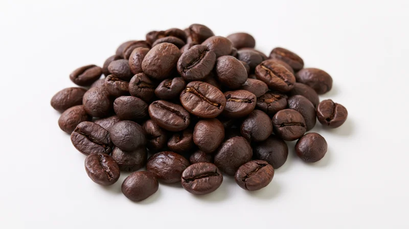 Dark roasted coffee beans piled loosely on a white surface