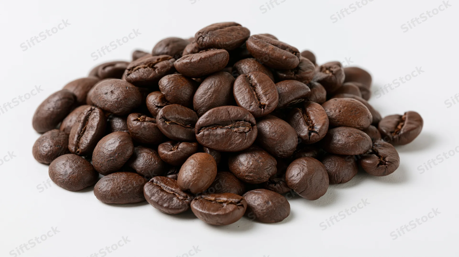 A small loose pile of dark roasted coffee beans heaped together on a white surface
